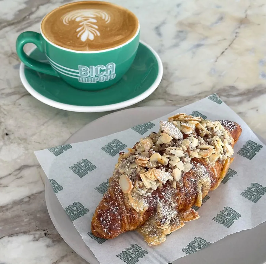 Café na chávena verde BICA e croissant de amêndoas